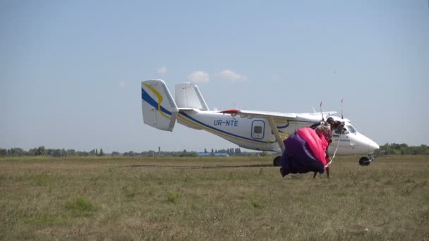 Скайдайвер с парашютом после приземления проходит мимо самолета — стоковое видео