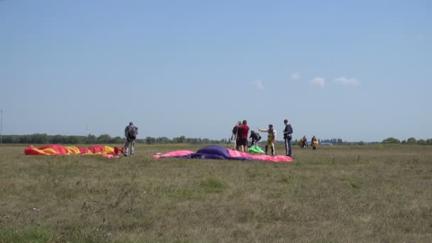 Десантники, після посадки, з ентузіазмом вітають один одного. На землі є яскравим парашути — стокове відео