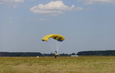 Bir paraşütçü destekli paraşüt sahaya iniyor