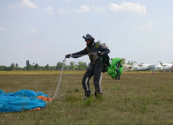 Parašutistické stojí po přistání na hřišti v gear a unfastens padák. — Stock fotografie