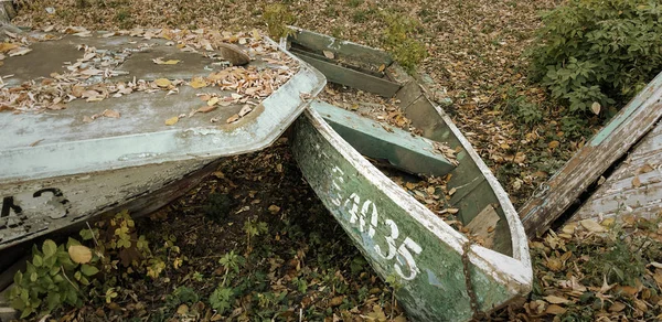 Hösten. Gamla övergivna båtar på stranden, täckt med höstlöv. — Stockfoto