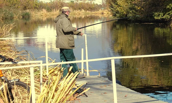 Pescatore in una soleggiata giornata autunnale sulle rive del fiume — Foto Stock