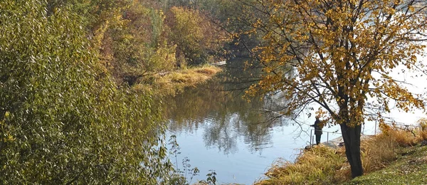 Pescatore con una canna da pesca in una giornata autunnale sul fiume . — Foto Stock