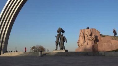 Kiev 'deki Halkın Dostluk Kemeri. Yürüyen insanlar ve çocuklar anıtın yanında oynuyorlar.