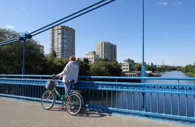Köprüde duran bisikletli bir kadın Tsna Nehri ve Tambov 'un manzarasına hayran.