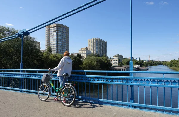 Köprüde duran bisikletli bir kadın Tsna Nehri ve Tambov 'un manzarasına hayran.