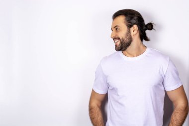 Yakışıklı adam gülümseyerek, uzakta, profil seyir beyaz bir arka plan üzerinde beyaz t-shirt