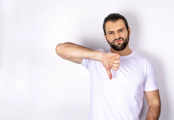 handsome man in white t-shirt over white background showing dislike