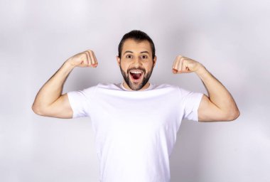 Beyaz arka plan üzerinde beyaz t-shirt yakışıklı adam pazı, güçlü silah gösterir