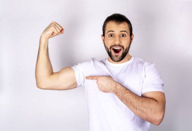 Beyaz arka plan üzerinde beyaz t-shirt yakışıklı adam pazı, güçlü silah gösterir