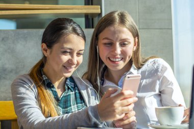 bir kafede iki güzel kızın telefonu elinde bir smartphone cep telefonu ile sms yazmak