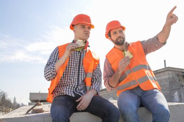 iki işçi Kasklar Öğle Yemeği, dinlenme, beton levhalar üzerinde oturmak