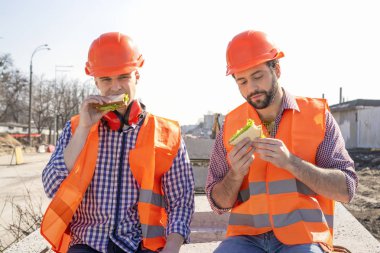 iki işçi Kasklar Öğle Yemeği, dinlenme, beton levhalar üzerinde oturmak