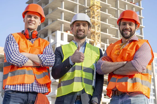 Ingenieros Trabajadores Masculinos Cascos Miran Cámara Sonríen Sitio Construcción — Foto de Stock