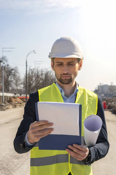 male engineer with drawings in a white helmet smiling