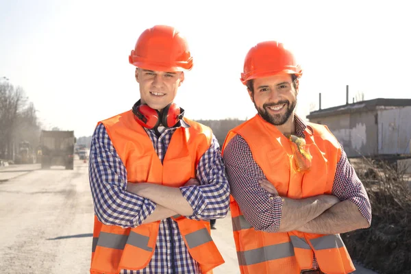 Ingenieros Trabajadores Masculinos Cascos Miran Cámara Sonríen Sitio Construcción — Foto de Stock