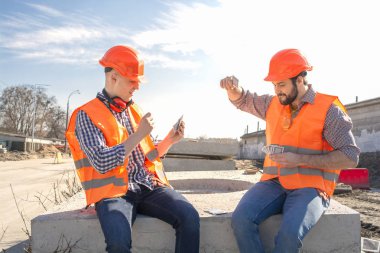 kask lı iki çalışan mühendis bir şantiyede kart oynuyor