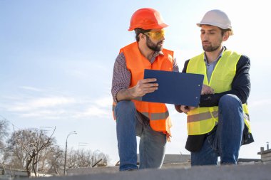 Erkekler, mühendisler, kask işçiler, birlikte bir inşaat alanında kendi yönetici ile, çizimler bakıyor, onarımlar