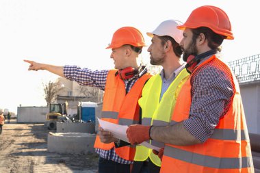 Erkek inşaatçılar işçiler mühendisler bir inşaat yerinde kask çizimleri görünümlü