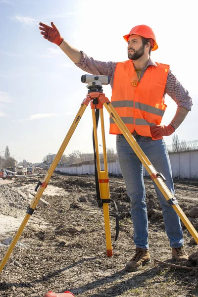 male surveyor engineer with a device working on a construction site in a helmet