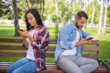 telefonda konuşurken bir bankta bir parkta sevgi dolu çift, yakışıklı adam ve kız