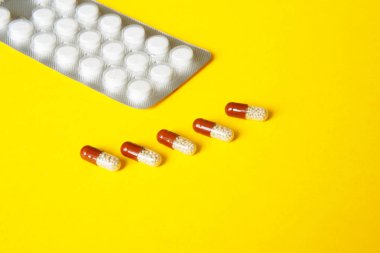 Sağlık sorunları. Hap ve kapsül yalan üzerine sarı bir arka plan ile blister.