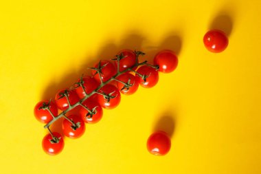 Kiraz domates ve sarı bir arka plan üzerinde iki ayrı domates yalan bir dalı.