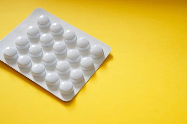 White packing of tablets - a blister lies on a yellow background