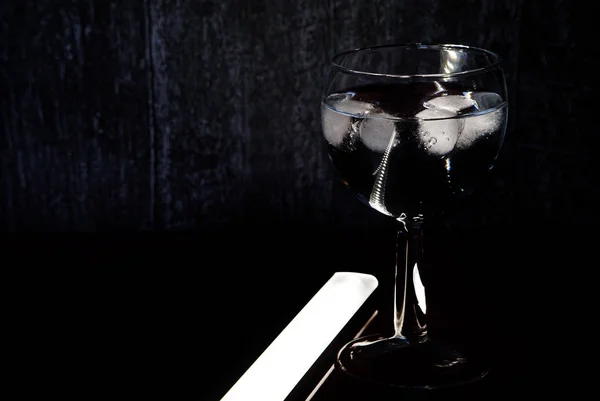 Glass on a leg with a cooling drink stands in a nightclub.