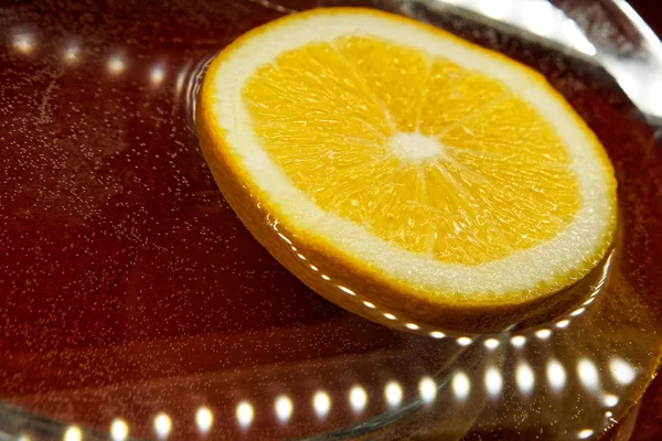 Slices of orange lie in the water next to the LEDs on. Light, orange and reflections.