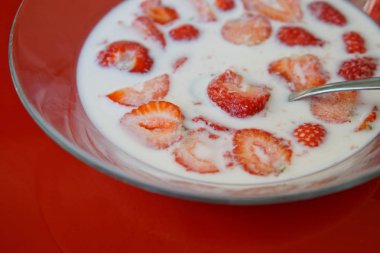 Doğru beslenme. Çilek, süt ve kırmızı bir arka plan üzerine bir kaşık ile şeffaf plaka.                        