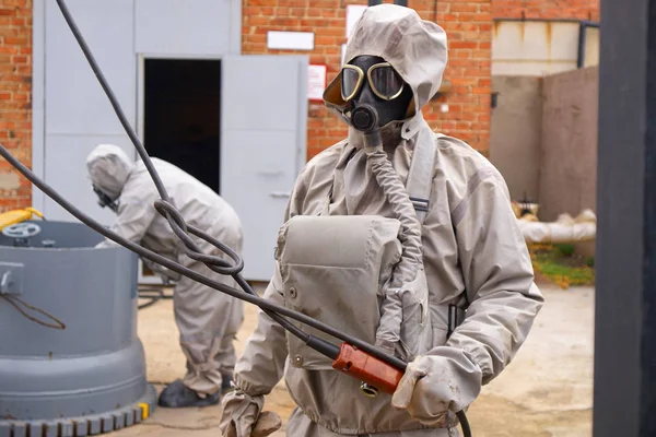 Man works in a white chemical protection suit and a gas mask. Chemical Hazards.