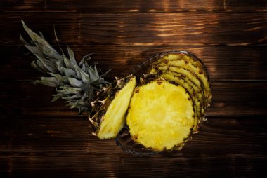 Olgun bir ahşap arka plan şeffaf bir tabağa ananas dilimleri. Sağlıklı gıda. Teslimat ve meyve satışı.                           