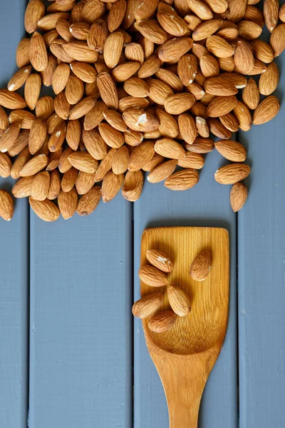 Миндальные орехи и шпатель серая деревянная поверхность. Здоровое питание. Вертикаль — стоковое фото
