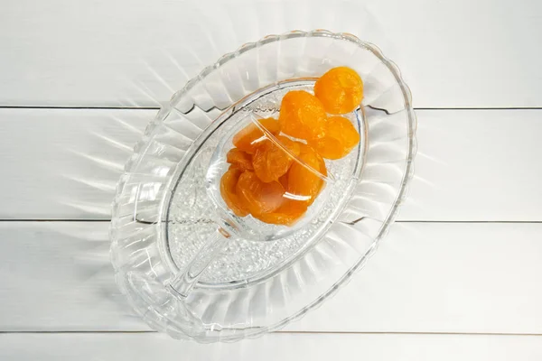 Fruits secs - abricots dans une assiette transparente sur une surface en bois blanc. Vue d'en haut. Style champêtre — Photo