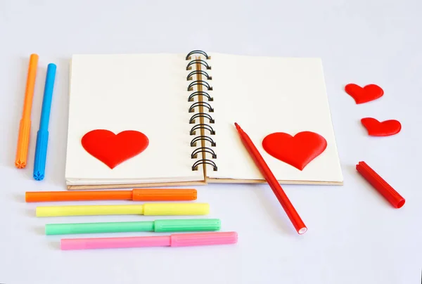 Notebook with markers and hearts on a white background. Template for Valentine\'s Day greetings. Form.