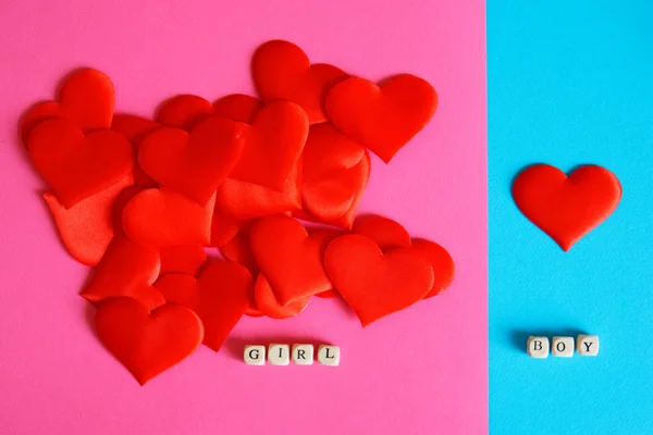 Red hearts on a blue and pink surface. Love and gender differences. Congratulations on Valentines Day.