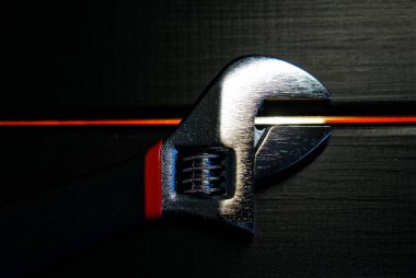 Atölye bir siyah ahşap yüzey üzerinde ayarlanabilir anahtarı yatıyor. Tamirci ve birleştiriciyi çalışmalarını için aygıt. Yakın çekim                               