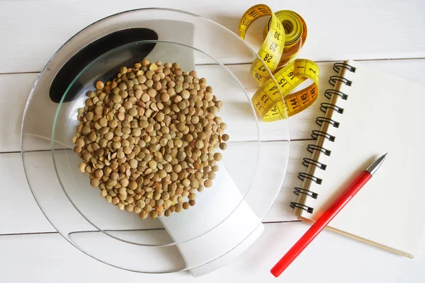 Counting calories, fat, protein and carbohydrates in food. Lentil seeds on kitchen scales. Slim figure, weight loss, diet and proper nutrition.