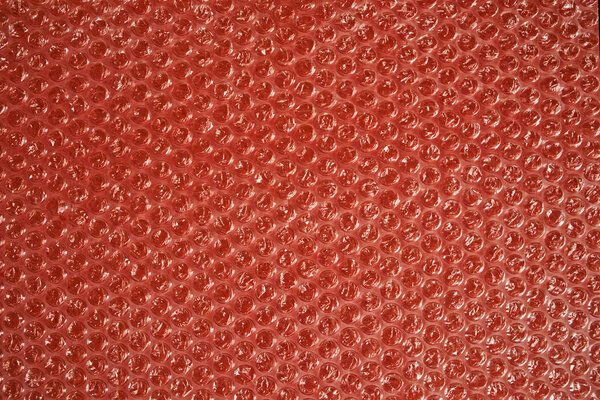Bubble wrap on a red background. Texture and background. Packing bubble film.                               