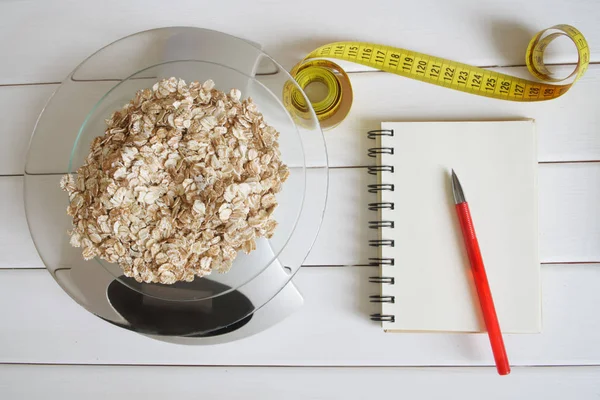 Counting and recording the amount of carbohydrates, calories, proteins and fats in food. Flakes from four cereals on kitchen scales. Oatmeal, wheat, barley and rye. Slim figure, fitness, weight loss, diet and proper nutrition