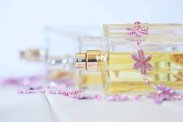 Transparent bottles with perfume sprays lie on a white surface. Beauty industry. The picture in bright colors.