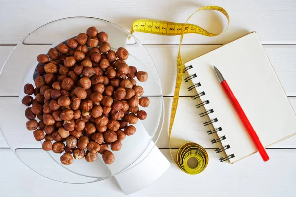 Counting and recording the amount of fat, calories, protein and carbohydrates in food. Hazelnut on kitchen scales. Slim figure, fitness, weight loss, diet and proper nutrition.