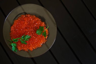 Kırmızı havyar Somon Balık ve maydanoz üzerinde siyah bir arka plan şeffaf bir tabak içinde bırakır. Sağlıklı gıda                              