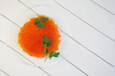 Kırmızı somon havyar ve maydanoz üzerinde beyaz bir çapraz arka plan şeffaf bir tabak içinde bırakır. Sağlıklı gıda.                           