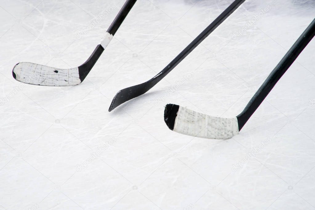 Three black ice hockey sticks on the court. Preparation for training in an open area. Winter sports.                            