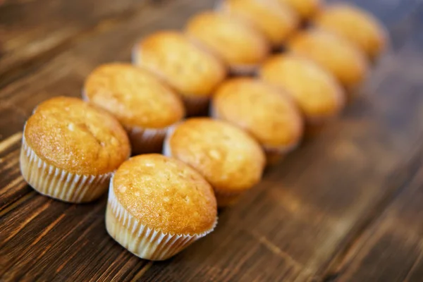 Läckra gyllene muffins på en yta av trä av furu styrelser. Välsmakande och hälsosam mat. Diagonal perspektiv och kort skärpedjup. — Stockfoto