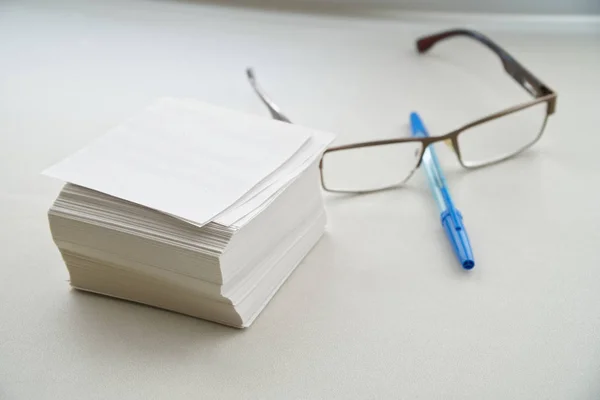 Een stapel lakens voor records, glazen en een vulpen zijn op een witte tafel bij het raam in het kantoor. — Stockfoto