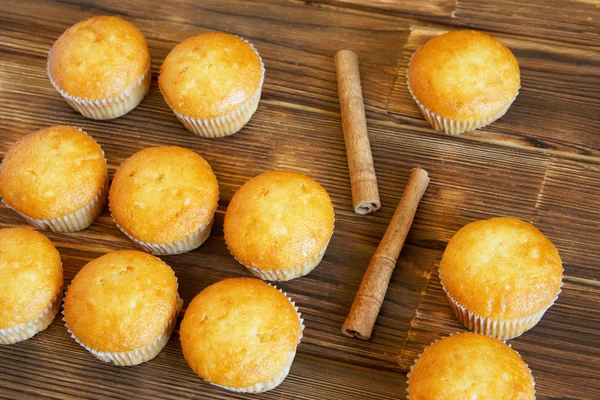 Palitos de canela y cupcakes dorados se encuentran en la superficie de madera de tablones de pino. Comida sabrosa y saludable . —  Fotos de Stock