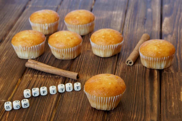Muffins dorados frescos con palitos de canela se encuentran en una superficie de madera hecha de tablas de pino. Buen apetito. Comida sabrosa y saludable . —  Fotos de Stock